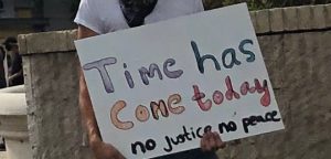 Protestor on Hollywood blvd. holds up a sign: "time has come today. No justice, no peace"