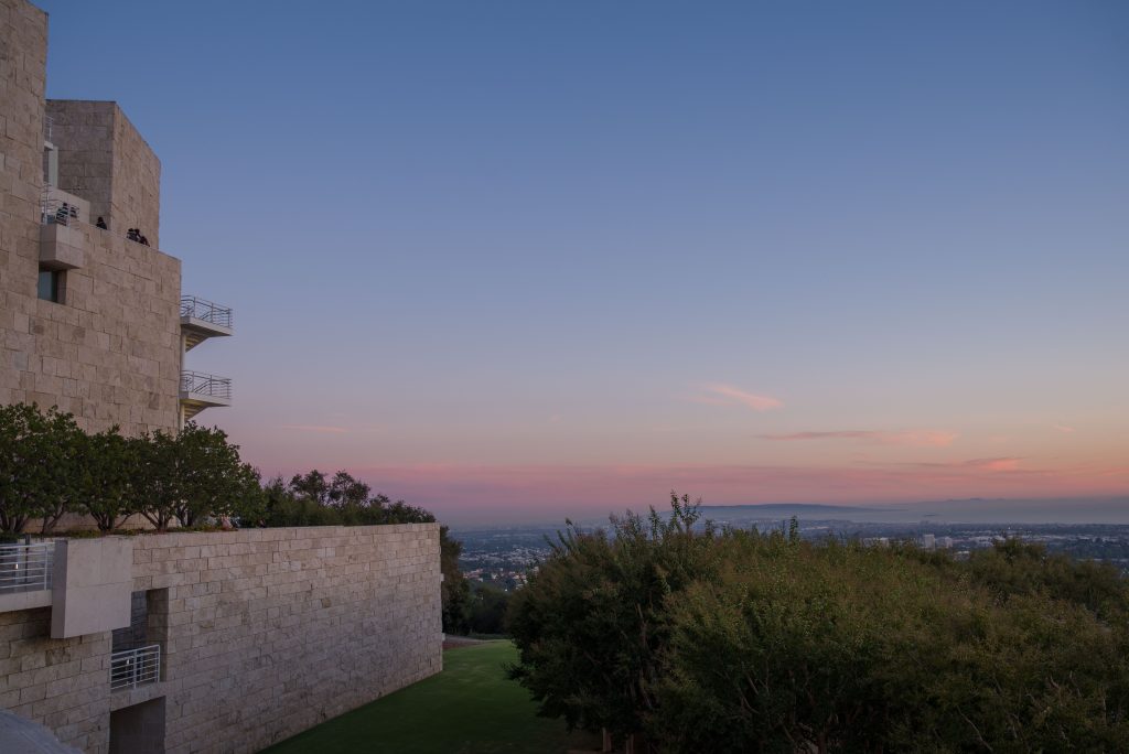 The sun sets in the background of a view from the Getty Museum, highlighting the sharp edges and cool colors of the museum's modern design. The Getty Center is a beautiful example of modern architecture, perfectly combining nature and design into a serene environment. Photo by Katelyn Michel/BruinLife.
