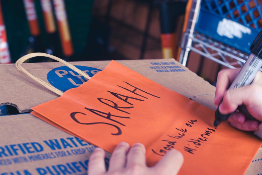 A caring gesture is captured as a Duffl worker writes a personal note of encouragement on a bright orange card, wishing "Sarah" good luck on her midterms. It&squot;s a simple yet touching reminder of the support that Duffl workers provide during stressful times. Photographed by Olivia Maizes/BruinLife.