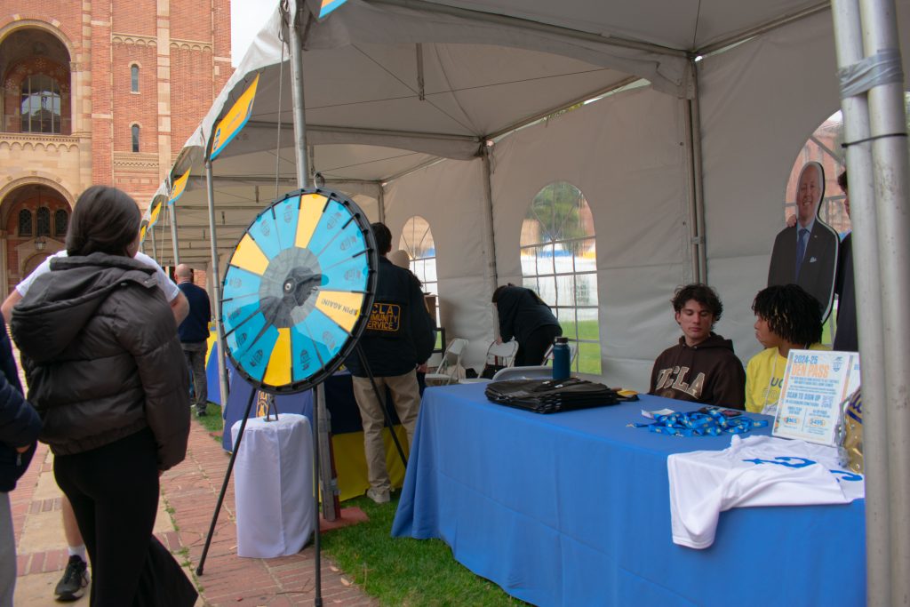 UCLA's Den tent is set up with a colorful prize wheel and information table.