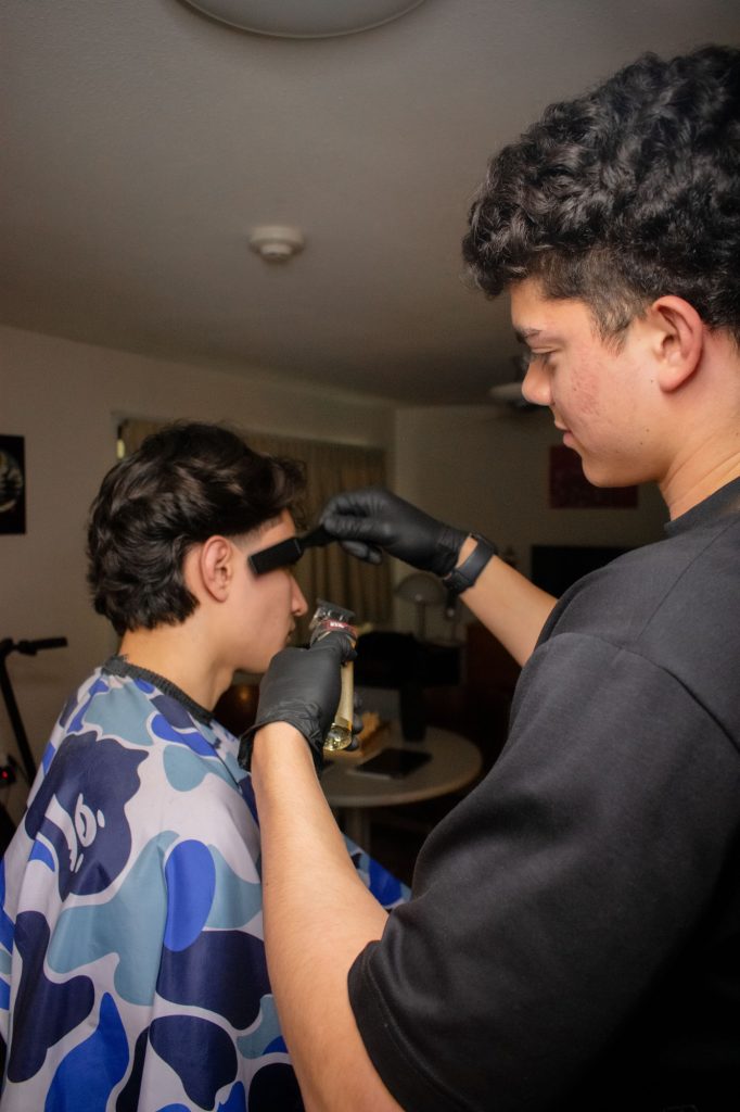 Diego Duarte interacts with a client as he finishes off a haircut. Duarte ensures his clients leave with a detailed, clean look. Photographed by Emily Chandler/BruinLife