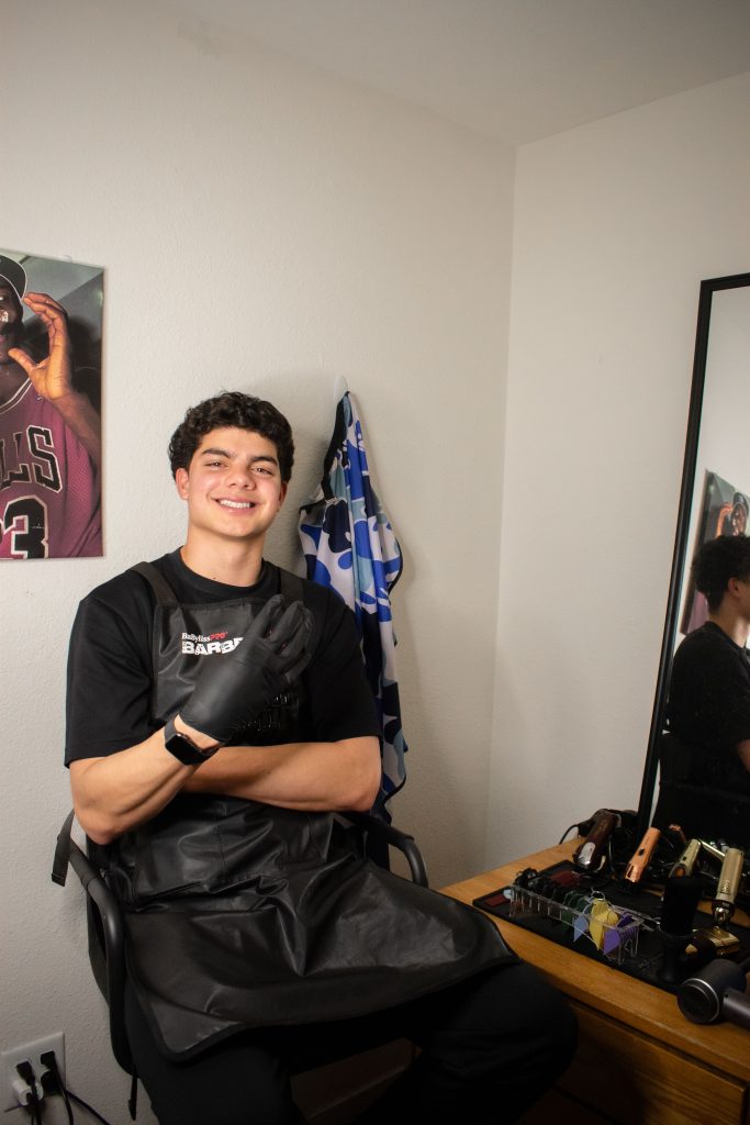 Diego Duarte smiles at the camera as he sits in his own barber chair. He held up a “4” as a homage to the notorious “4s up.” Photographed by Emily Chandler/BruinLife