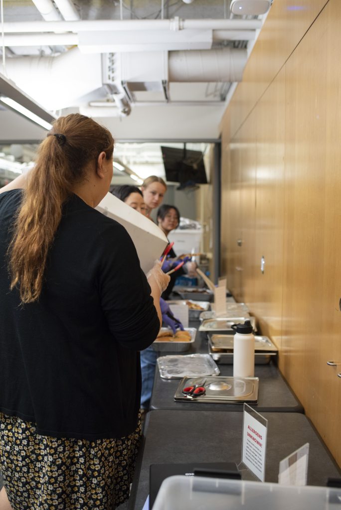 A volunteer consults with officers and fellow volunteers before the start of the distribution period. Many of Bruin Dine’s volunteers come in regularly, forming a close-knit community. Photographed by Julia Gu/BruinLife