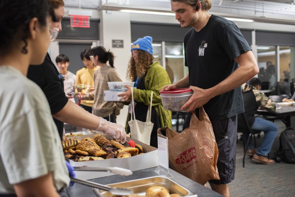 A volunteer introduces the pastry options to the night’s diners. Diners will often take a croissant or a muffin for a midnight snack or the next day’s breakfast. Photographed by Julia Gu/BruinLife