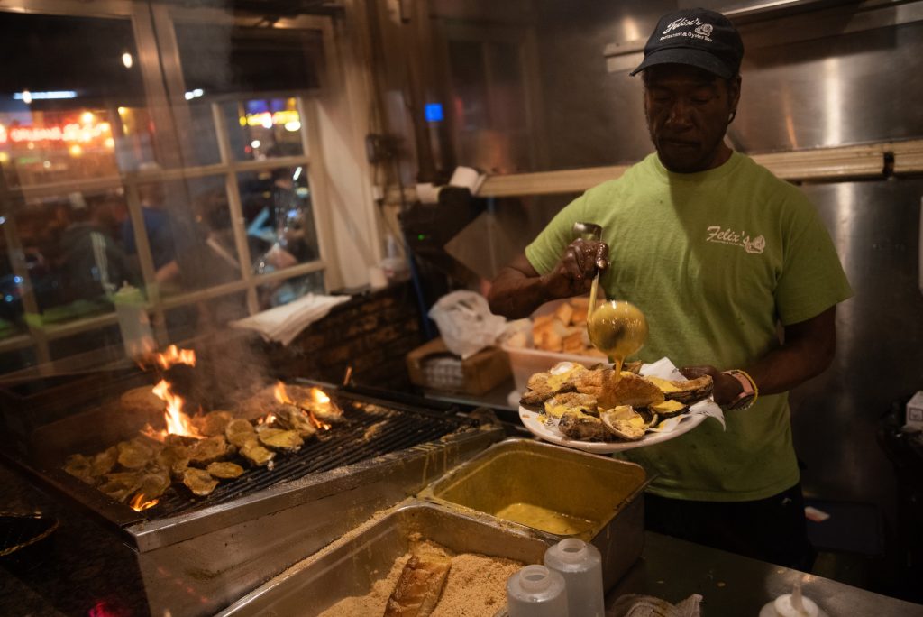 Chef Kevin Scott prepares char-broiled oysters over a flaming grill. Photographed by Finn Martin/BruinLife.