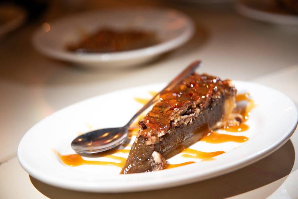 The Creole Pecan Pie rests elegantly on the plate. This dessert is a delicacy that is bound to satisfy any lingering desires from your dinner at Felix's. Photographed by Finn Martin/BruinLife.