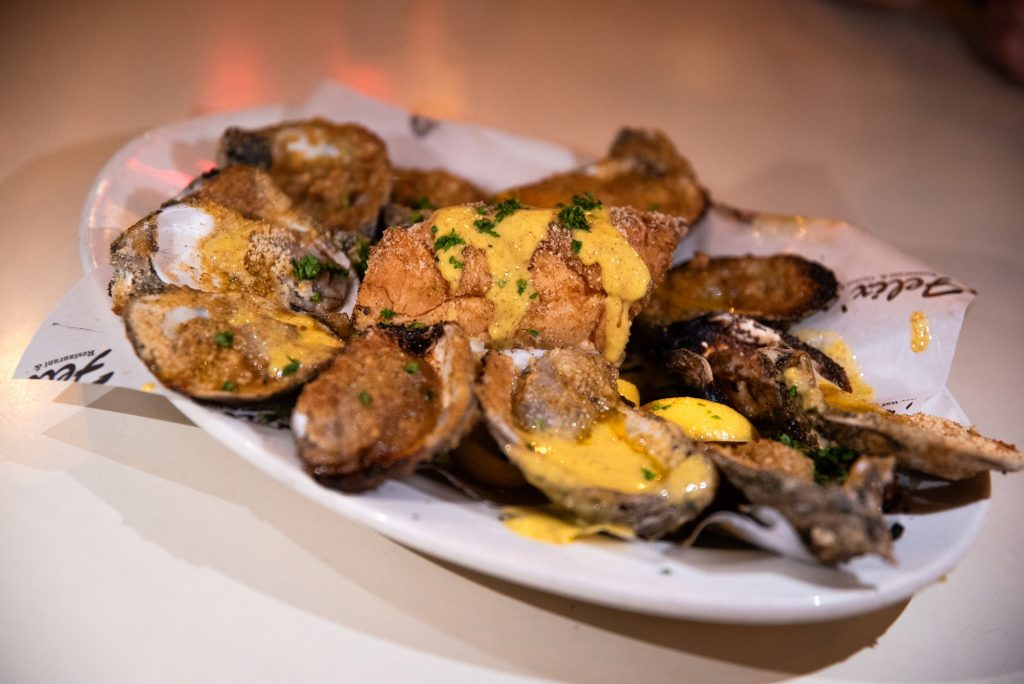 The char-grilled oysters are served with a parmesan sauce and breadcrumbs. Photographed by Finn Martin/BruinLife.
