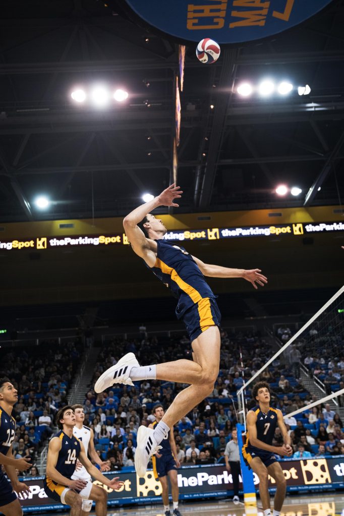 UC Irvine #9 Nolan Flexen leaps into action, preparing to deliver a powerful spike over the UCLA blockers. Photographed by Ryan Zhang/BruinLife