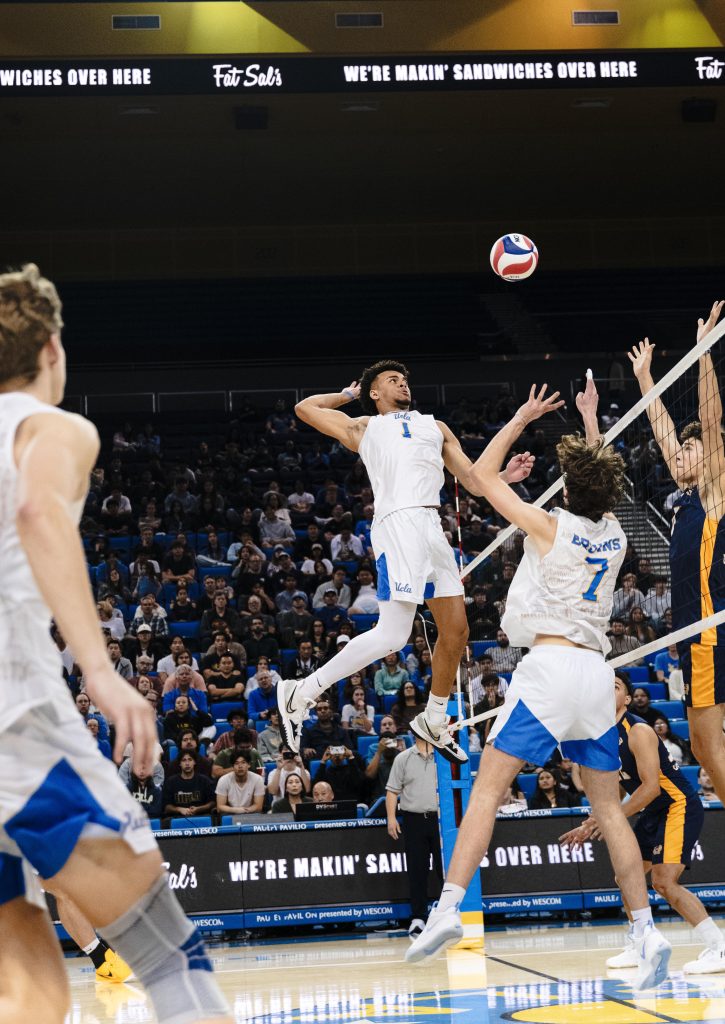 UCLA #1 Cameron Thorne jumps high to spike the ball over UC Irvine blockers. Photographed by Ryan Zhang/BruinLife