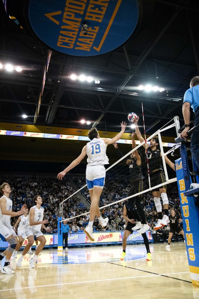 UCLA right side hitter #19 David Decker attempts to block Long Beach State's #8 Sotiris Siapanis' tip over the net. Photographed by Ryan Zhang/BruinLife.
