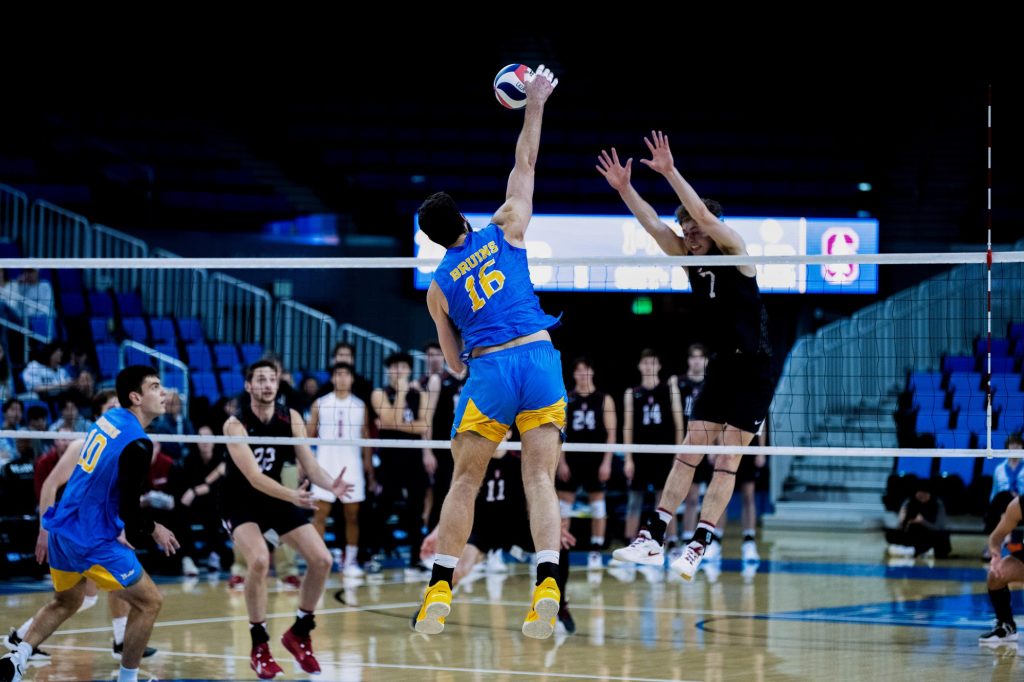Ido David soars above the net for a powerful spike against Stanford's defense. Photographed by Amy Miranda/BruinLife
