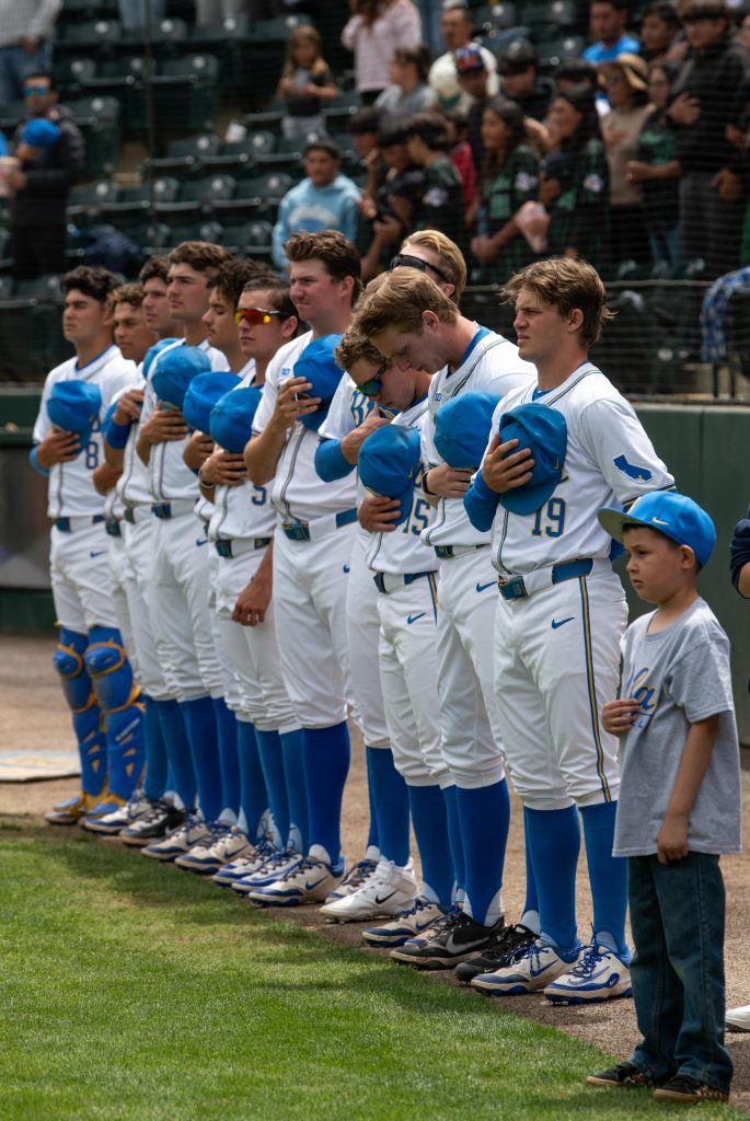 UCLA players stand for the national anthem prior to the first pitch. Photographed by Maia Salti/BruinLife