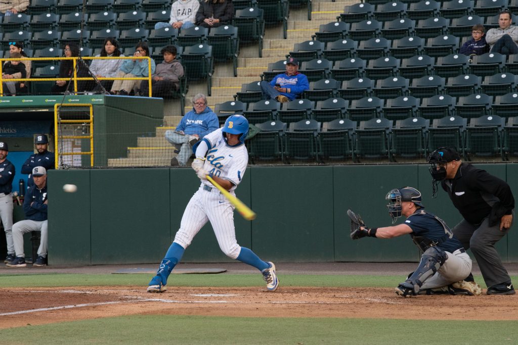 UCLA player swings bat across home plate.