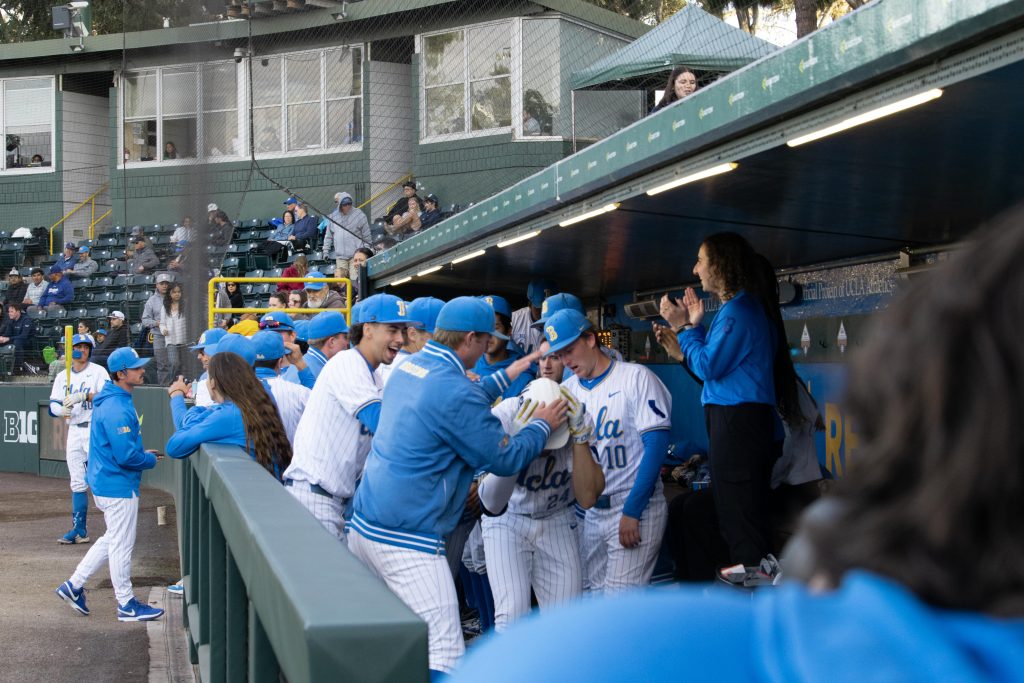 UCLA players celebrate in dug out after home run.