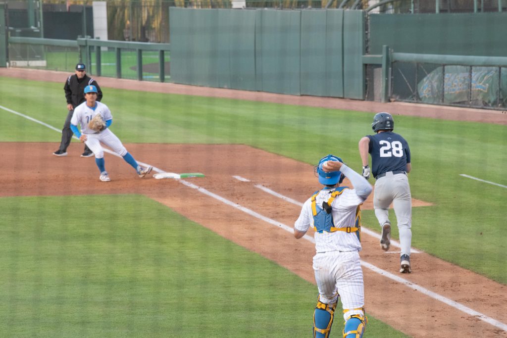 UCLA catcher throws ball to first baseman as Penn state player runs down the 1st baseline.