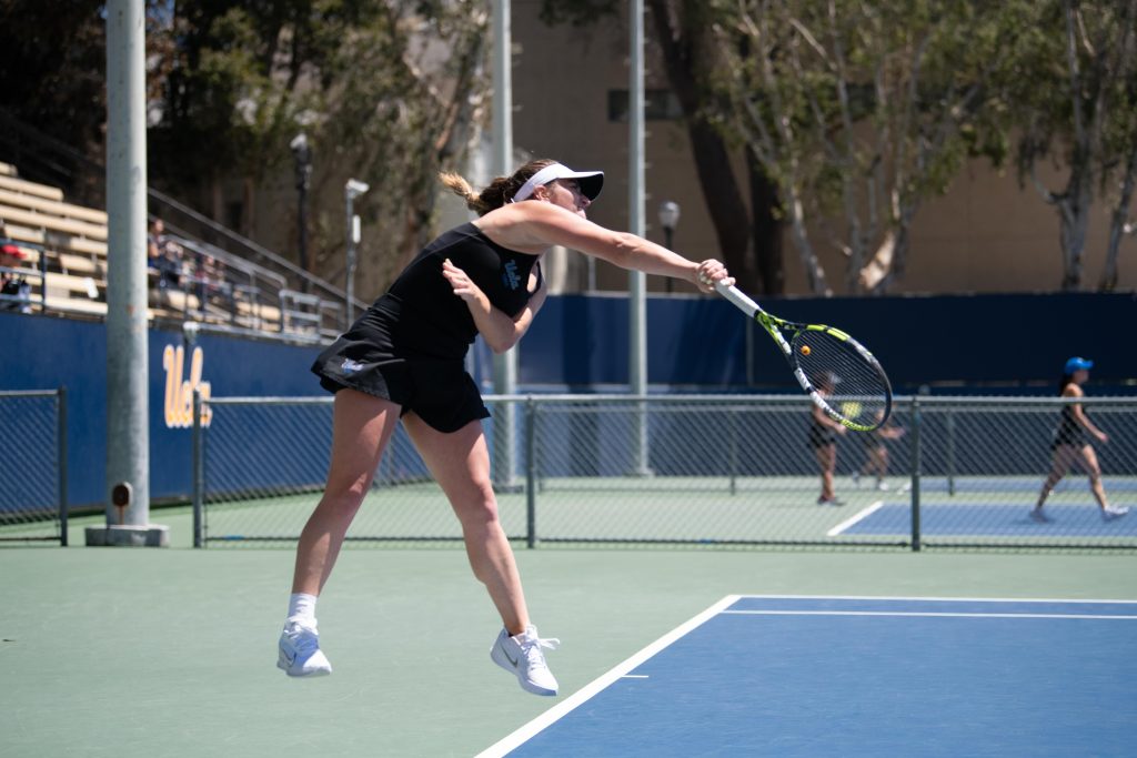 UCLA player swings racket as she serves the ball in.