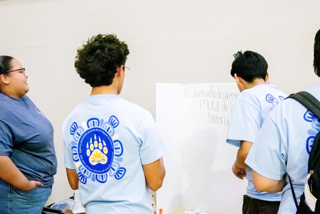 Holding jigsaw pieces on which they have written their thoughts, Latinx admit students express the legacy they want to leave behind in history on an inspirational trifold at check-in. Photographed by Julia Gu/BruinLife.