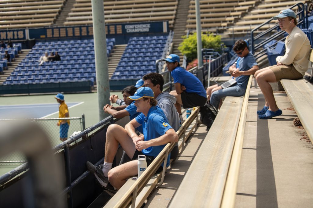 After winning his doubles match, Johnson joins his teammates in cheering on the singles matches. Photographed by Mira Daya/BruinLife