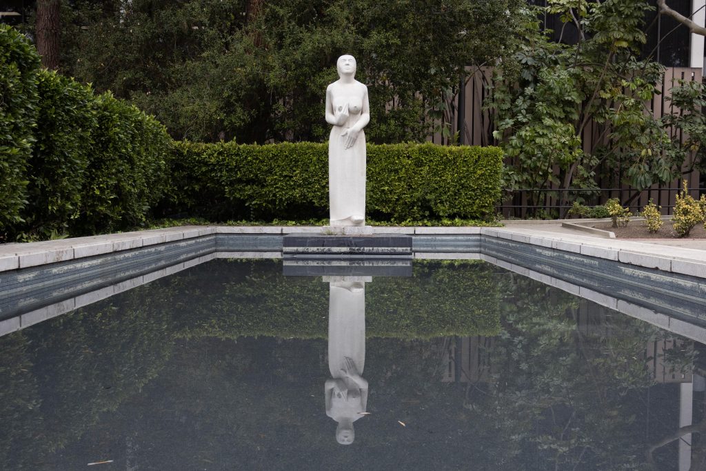 Mulier, a piece by British sculptor Eric Gill, stands proudly with its reflection by the Charles E. Young Research Library. Photographed by Julia Gu/BruinLife.