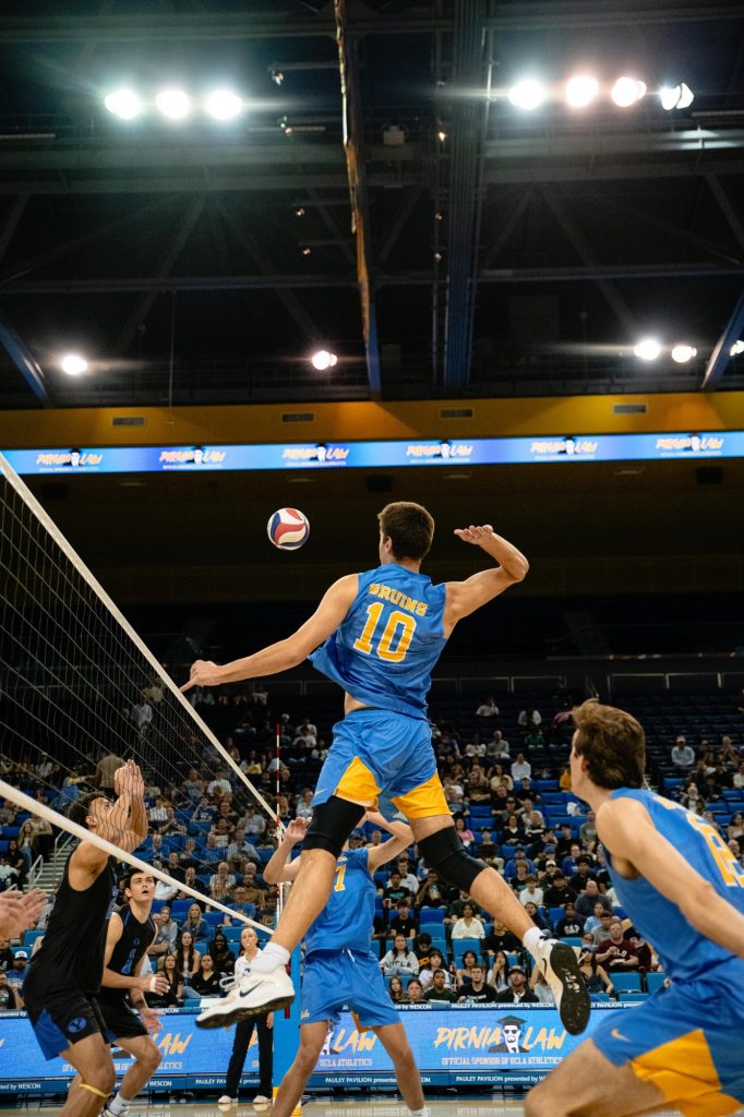 UCLA’s Sean McQuiggan leaps high down the middle to deliver a powerful spike. Photographed by Ryan Zhang/BruinLife.