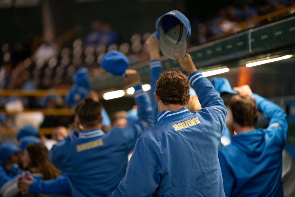 UCLA players lift their caps in dug out as they rally in players post inning.