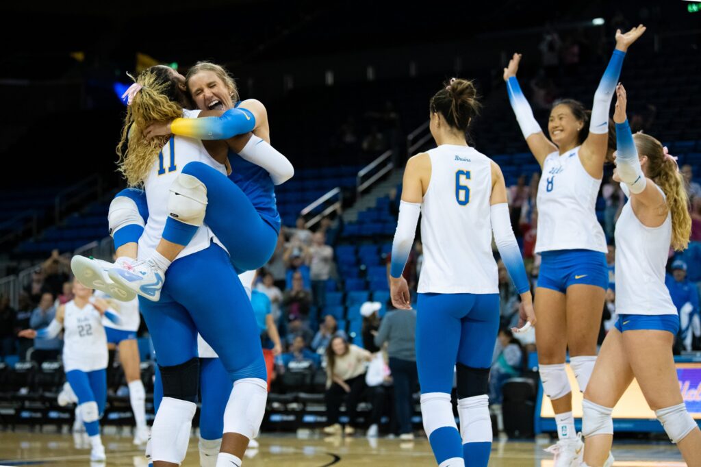 UCLA's starting lineup rejoices in cheers and lifting hugs after 3 set sweep victory. Photo by Luana Caravalho