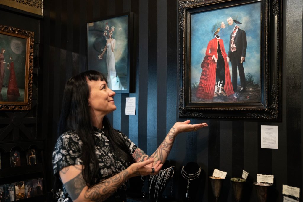 Los Angeles-based artist Liz Huston poses with one of her pieces, titled "The Dreamkeepers." She commonly draws from themes of spirituality to create beautifully haunting scenes in her work. Photographed by Julia Gu/BruinLife.