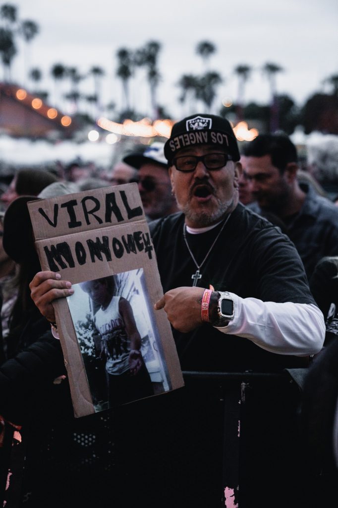 A passionate fan of The Pretenders excitedly screams as the band takes the stage, showcasing his handmade fan poster. Photographed by Cathryn Kuczynski/BruinLife.