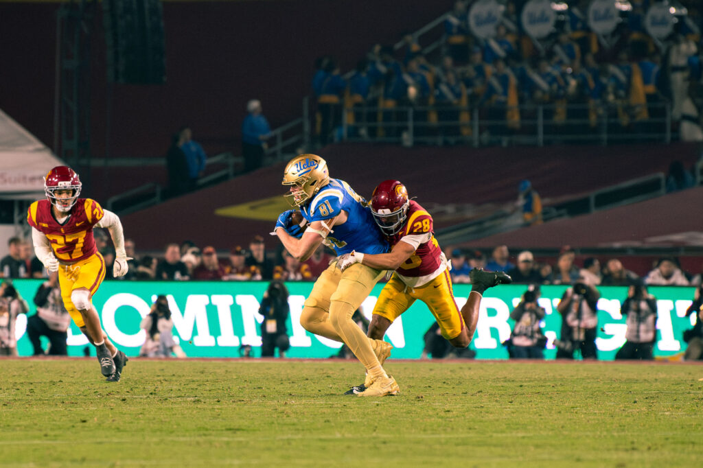 UCLA's Hudson Habermehl breaks a tackle as USC defenders give chase. Photographed by Catherine Rodriguez/BruinLife.