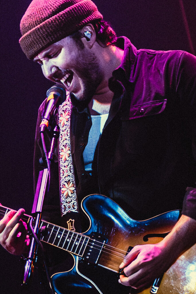 Paul Colgan leans into a high-energy guitar moment during the band’s performance. Colgan’s playing adds a more upbeat edge to the band’s live sound. Photographed by Amy Miranda/BruinLife