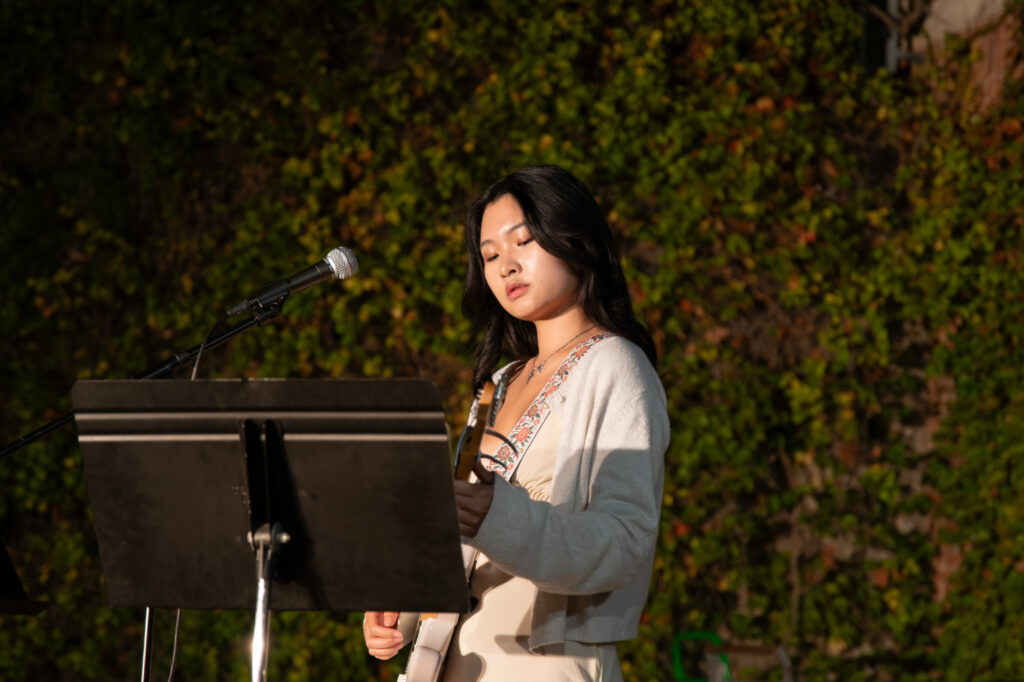 Fiona Kuo, the lead vocalist of 9 Ball, immersed in her performance at Fowler Out Loud. She was pictured alongside her guitar as she sang a popular crowd-pleasing cover. Photographed by Siena Hunt/BruinLife