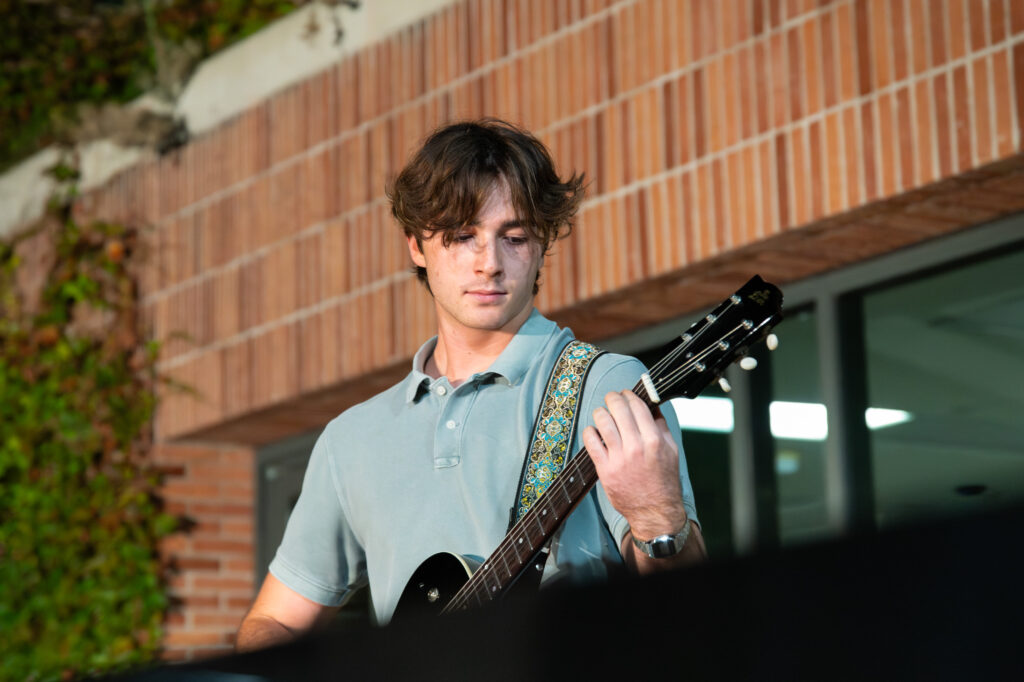 James Blue, the lead guitarist, performing an original with his bandmates. Blue is seen pictured with his guitar, concentrated on his performance. Photographed by Siena Hunt/BruinLife