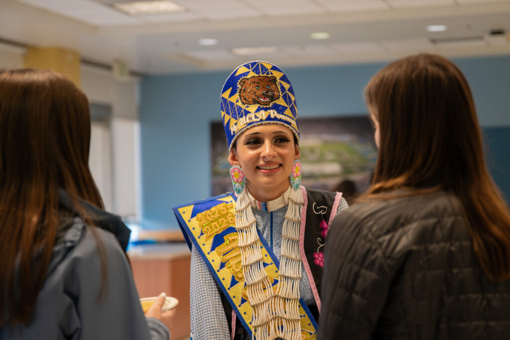 Lucy Garza, a UCLA graduate student, pictured talking to attendees of the event. Garza was crowned the 2025-2026 UCLA Powwow Princess last May and continues to educate and bring awareness to her community. Photographed by Siena Hunt/BruinLife