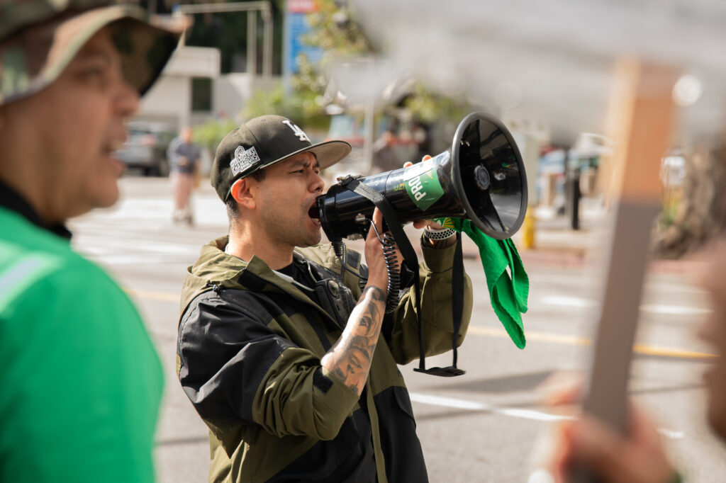One of the event volunteers seen leading the chant through a megaphone. Earlier, he was seen rallying the crowd with his energy and passion. Photographed by Siena Hunt/BruinLife