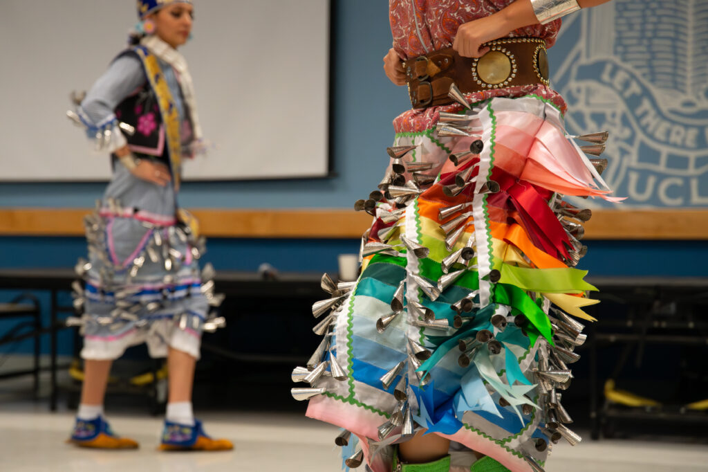 Two dancers pictured wearing traditional Jingle Dresses as they put on a special performance for the event. The performers showed the audience two dances choreographed to music. Photographed by Siena Hunt/BruinLife