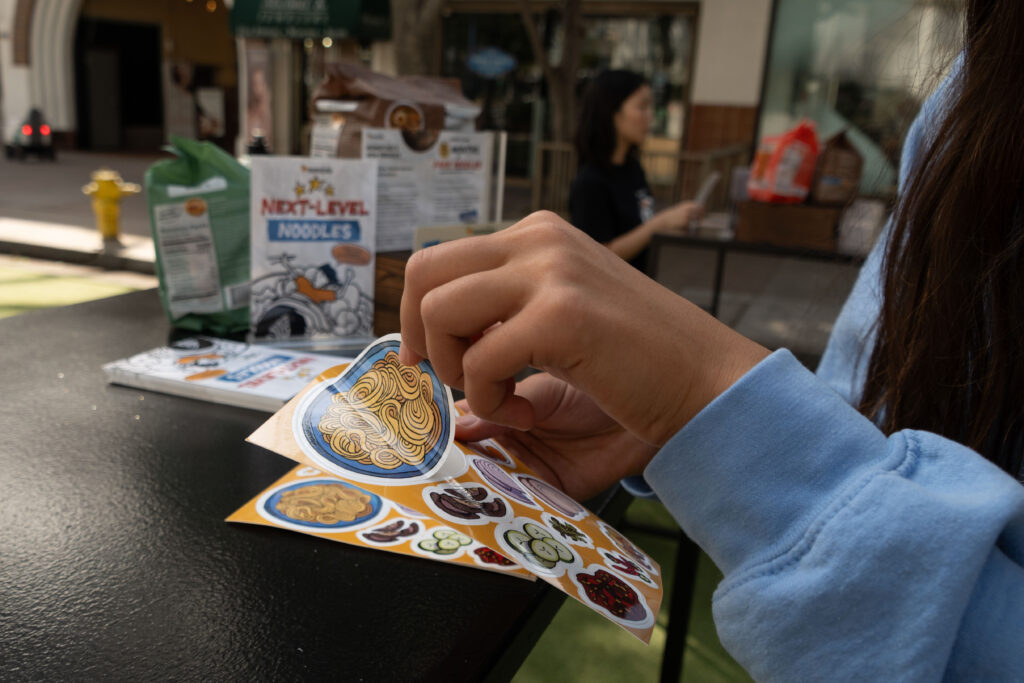 A student peels off a sticker at the pop-up event. As part of their promotional event, Momofuku set up a sticker bar for customer's to customize their own sticker. Photographed by Aamani Maddukuri/BruinLife.