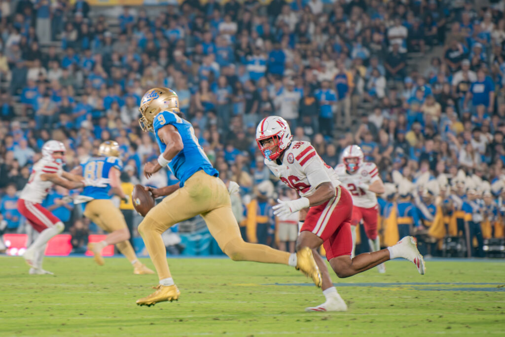 UCLA's quarterback Nico Iamaleava escapes pressure running away from Nebraska defense. Iamaleava is known for his scrambling ability. Photographed by Luana Caravalho/BruinLife.