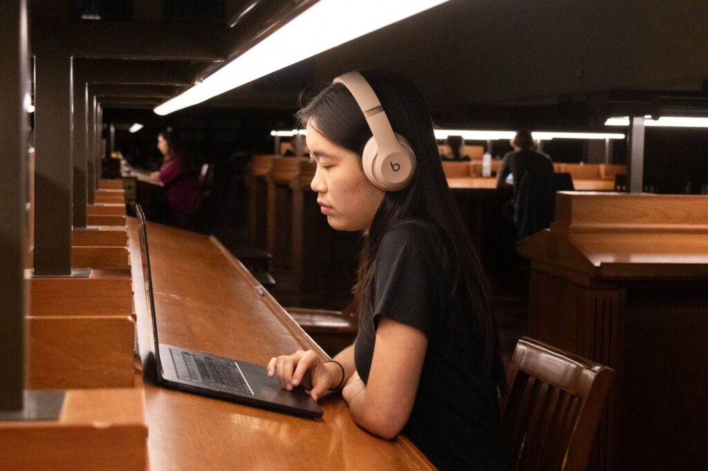 Second-year student Eunnie Wu tunes in to the Bruin Success Podcast on a rainy evening inside Powell Library. These episodes introduced students to unconventional fields — from cyborg anthropology to ocean storytelling — to expand their sense of what’s possible after graduation. Photographed by Jaclyn Wang/BruinLife.