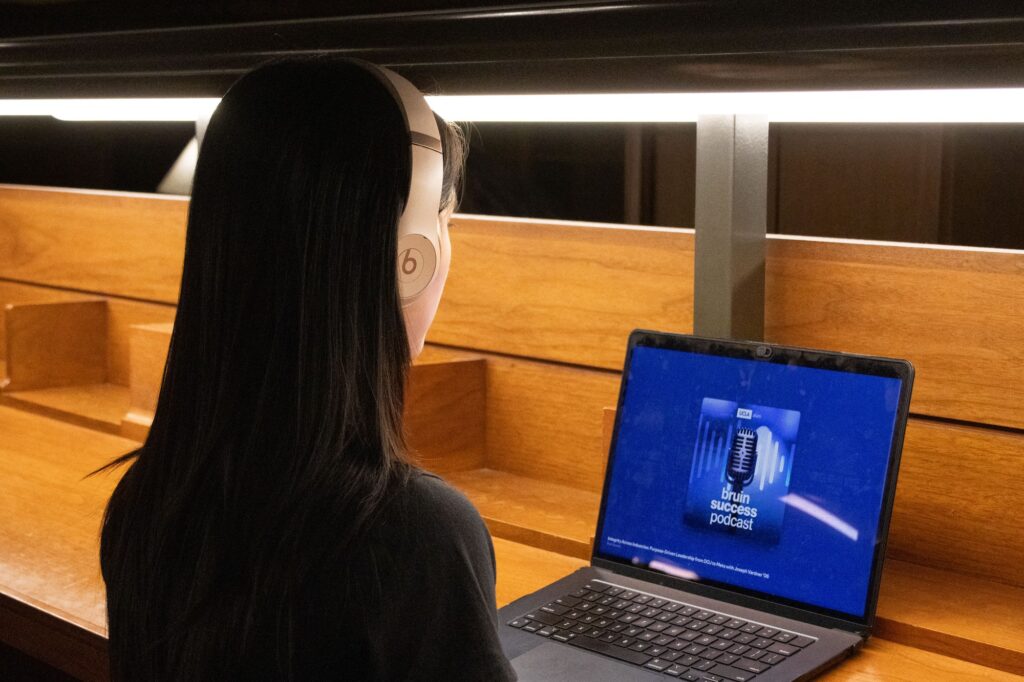 Second-year student Eunnie Wu tunes in to the Bruin Success Podcast on a quiet, rainy evening inside Powell Library. Photographed by Jaclyn Wang/BruinLife.
