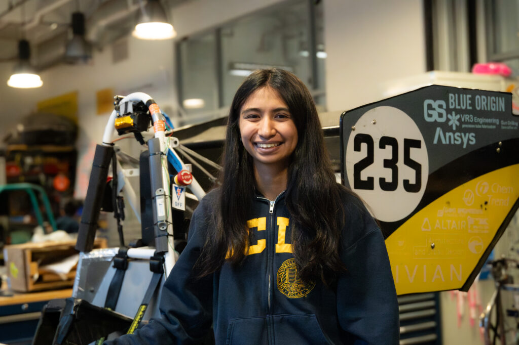 Fourth-year Mechanical Engineering student, Jenna Lacuata, pictured smiling in front of the latest Bruin Formula Racing car. Lacuata has been a part of BFR for three years and currently serves as a Vehicle Dynamics Team Lead. Photographed by Siena Hunt/BruinLife