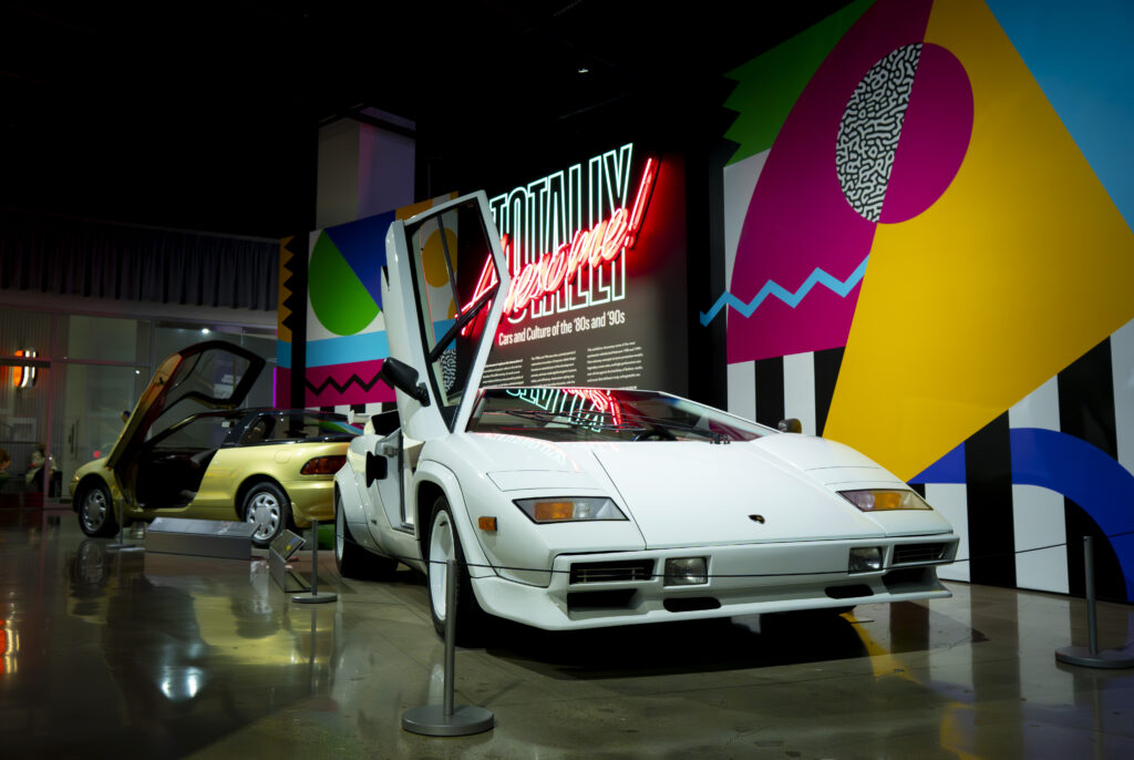 A white Lamborghini Countach pop against a neon mural. The exhibit captures the bold spirit of 80s and 90s car culture. Photographed by Janwayne Orme/BruinLife.