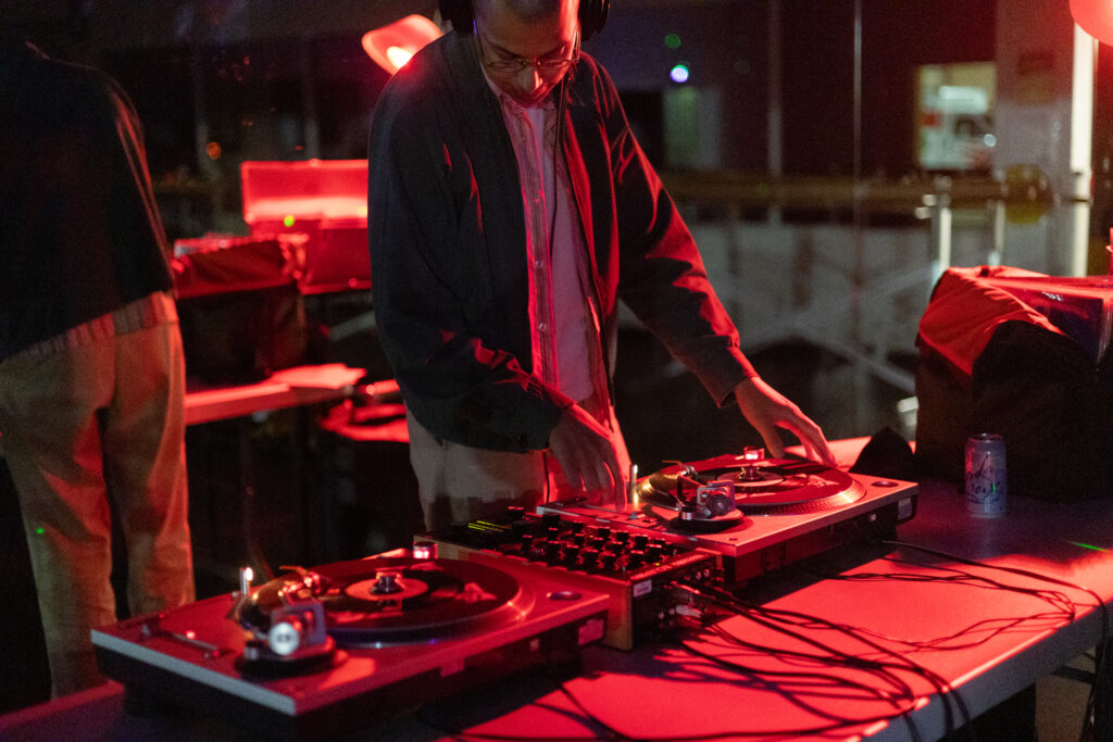 A DJ mixes vinyl records at a nighttime set. Photographed by Sapna Drew/BruinLife.